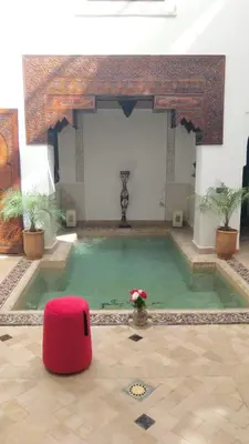 a large pool with a red ottoman in a room at Ryad Petit Palmier in Marrakech