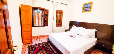 a bedroom with a white bed with a wooden headboard at Riad 1954 in Marrakech