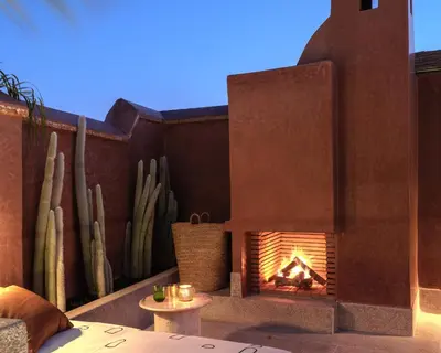 a fireplace on a patio with cactus in the background at Riad Brummell Medina in Marrakech