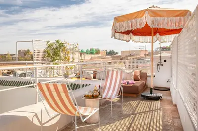 a balcony with two chairs and an umbrella at Riad Brummell Medina in Marrakech