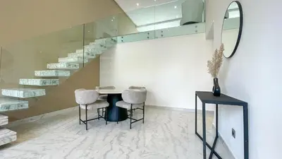 a room with a table and two chairs and a staircase at Duplex IKA - Appartement design à Marrakech in Marrakech