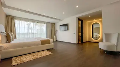 a bedroom with a bed and a chair and a window at Duplex IKA - Appartement design à Marrakech in Marrakech