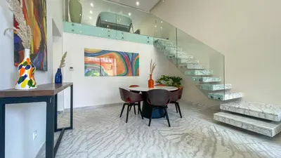 a dining room with a table and chairs and a staircase at Duplex Zoé - Contemporain et design à Marrakech in Marrakech