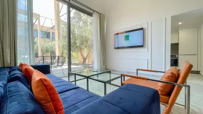 a living room with a blue couch and a tv at Duplex Zoé - Contemporain et design à Marrakech in Marrakech