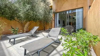 two chairs and a table in front of a building at Duplex Zoé - Contemporain et design à Marrakech in Marrakech