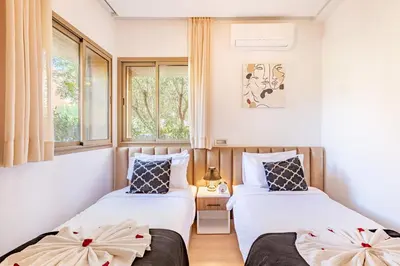 two beds in a room with two windows at Luxury Apartments Prestigia Pools Golf Fiber Parking in Marrakech