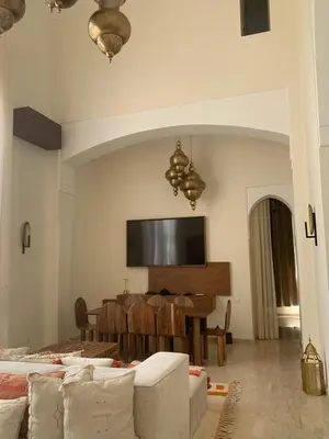 a living room with a table and a television on the wall at Villa Magnolia - Amelkis Golf in Marrakech