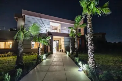 a house with palm trees in front of it at Konouz Palace in Marrakech