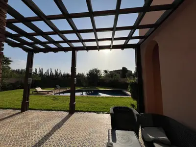 a patio with a pergola and a swimming pool at Konouz Palace in Marrakech