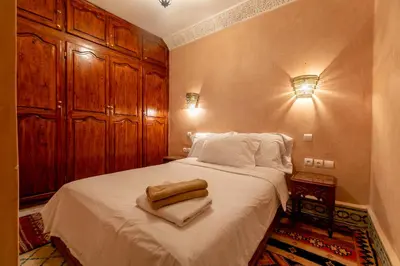 a bedroom with a bed with white sheets and wooden cabinets at Riad Dali in Marrakech