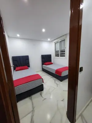 two beds in a room with marble floors at Magnifique appartement duplex à 5min de l'aéroport de Marrakech in Marrakech