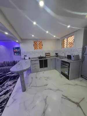 a large kitchen with a marble floor and a table at Magnifique appartement duplex à 5min de l'aéroport de Marrakech in Marrakech