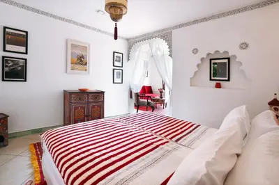 a bedroom with a bed with a red and white striped blanket at Le Bled Ferme in Marrakech
