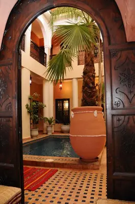 an entry to a house with a pool and a palm tree at Riad Hadda in Marrakech