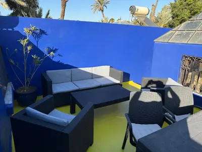 a patio with chairs and tables and a blue wall at Riad khoya magnifique in Marrakech