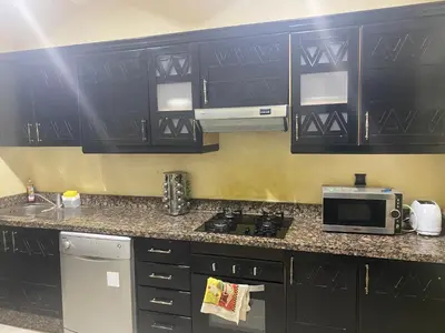 a small kitchen with black cabinets and a microwave at Charm & Chic Résidence in Marrakech