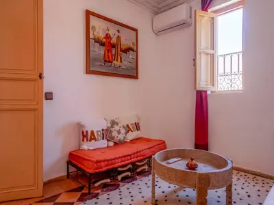 a living room with a red couch and a table at Riad Dar Nakhla in Marrakech