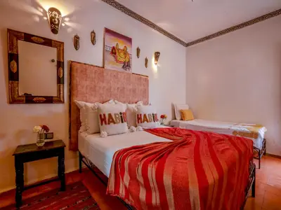 a bedroom with two beds and a mirror at Riad Dar Nakhla in Marrakech