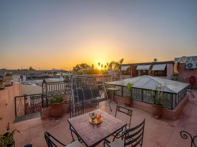 a balcony with a table and chairs and the sunset at Riad Dar Nakhla in Marrakech