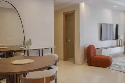 a living room with tables and chairs and a television at Appart très élégant avec piscine in Marrakech