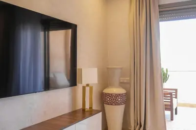 a living room with a tv and a lamp on a table at Appart très élégant avec piscine in Marrakech