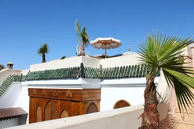a building with an umbrella and a palm tree at Riad El Morocco Hotel in Marrakech
