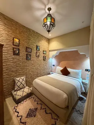 a bedroom with a large bed and a chandelier at Riad Touhfa Kasbah Marrakech in Marrakech