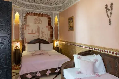 a room with two beds and a chair in it at Riad Arabesque in Marrakech