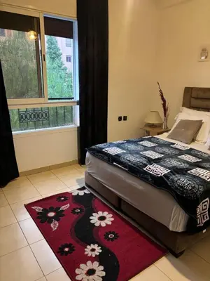 a bedroom with a bed with a red rug at belle appartement a Marrakech in Marrakech