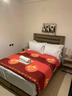 a bedroom with a bed with a red blanket with roses on it at belle appartement a Marrakech in Marrakech