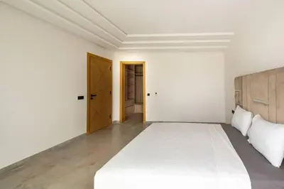 a white bedroom with a large bed and a door at Villa Design à Marrakech in Marrakech