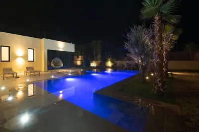 a swimming pool with blue lights in a backyard at night at Villa Design à Marrakech in Marrakech
