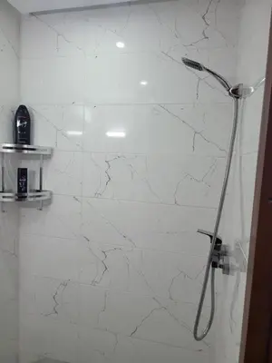 a shower in a bathroom with a white marble wall at Duplex+2 salles de bain à 5 min de l'aéroport in Marrakech