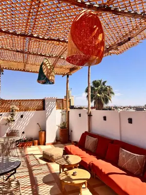 a living room with a red couch and an umbrella at Riad Jardin de Malia in Marrakech