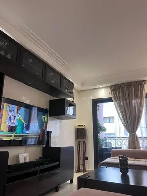 a living room with a couch and a tv in a room at Appartment Jnane Atlas in Marrakech