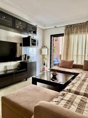 a living room with two beds and a flat screen tv at Appartment Jnane Atlas in Marrakech