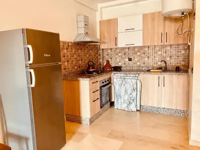 a kitchen with wooden cabinets and a stainless steel refrigerator at NOOR 5 Residence in Marrakech