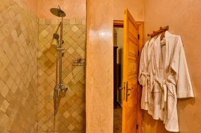 a bathroom with a shower and a robe on a door at Riad N 15 Zefriti in Marrakech