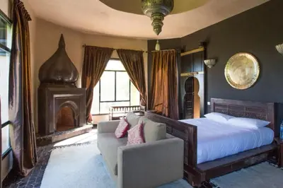 a bedroom with a bed and a couch and a fireplace at Villa Jude in Marrakech
