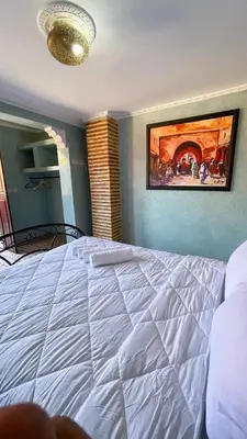 a white bed in a room with a painting on the wall at RIAD GJULJA in Marrakech