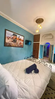 a large bed in a bedroom with a blue wall at RIAD GJULJA in Marrakech