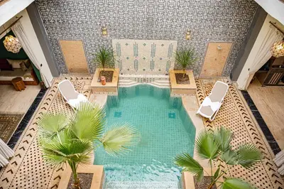 an overhead view of a swimming pool with chairs and palm trees at Riad Tonaroz in Marrakech