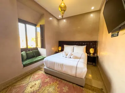 a bedroom with a bed and a couch and a tv at Riad Tonaroz in Marrakech