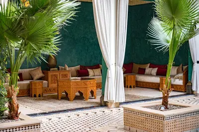 a living room with couches and palm trees at Riad Tonaroz in Marrakech
