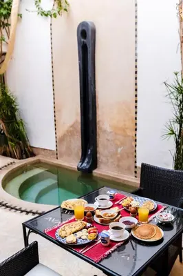 a tray of food on a table next to a swimming pool at Riad Rouge Gorge in Marrakech