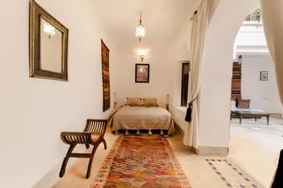 a bedroom with a bed and a chair and a rug at Riad Rouge Gorge in Marrakech
