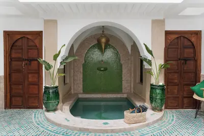 a swimming pool in a room with two plants at Riad of the Moon in Marrakech