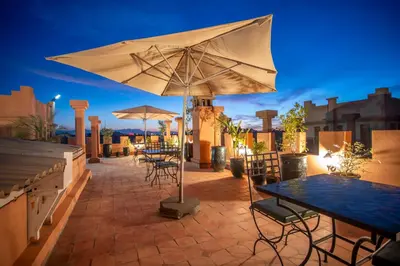 a patio with tables and umbrellas at night at Riad Azia in Marrakech