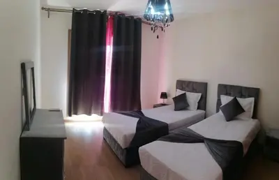 two beds in a room with a window at Appartement de rêve à Marrakech in Marrakech