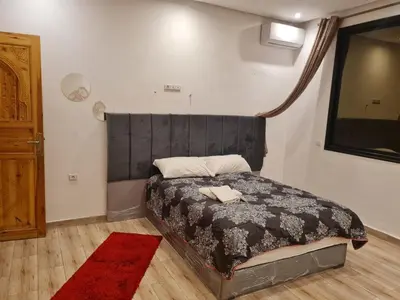 a bedroom with a bed with a black headboard and a red rug at Hostel Ghali & Private Rooms Gueliz in Marrakech